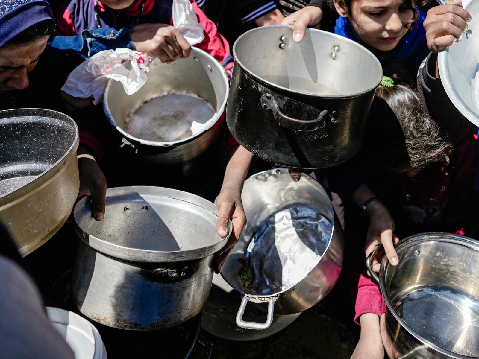 Kinderen houden hun lege potten vast in een gemeenschappelijke keuken in Noord-Gaza.