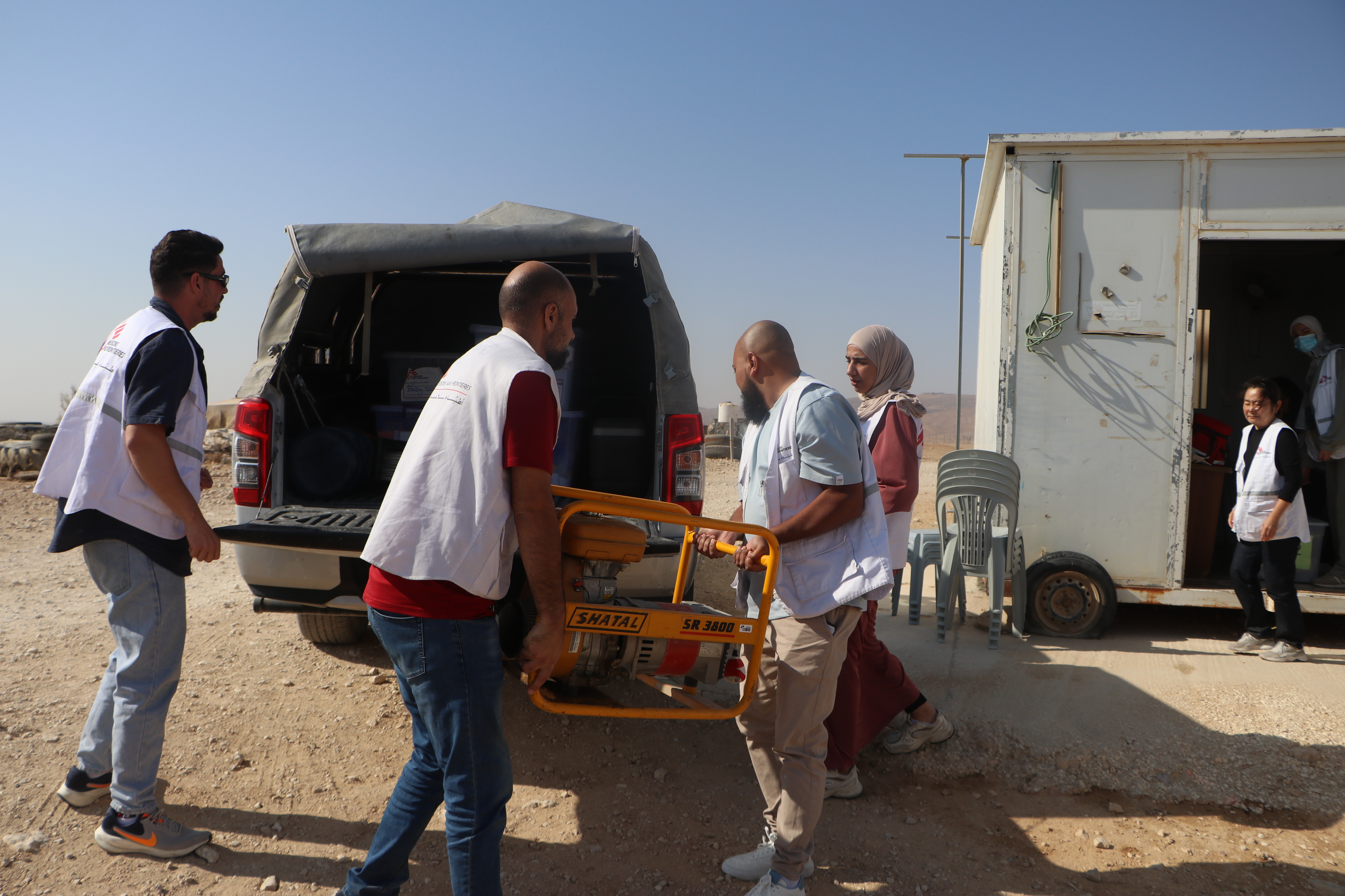 Medewerkers van Artsen Zonder Grenzen dragen een brancard in een ambulance 