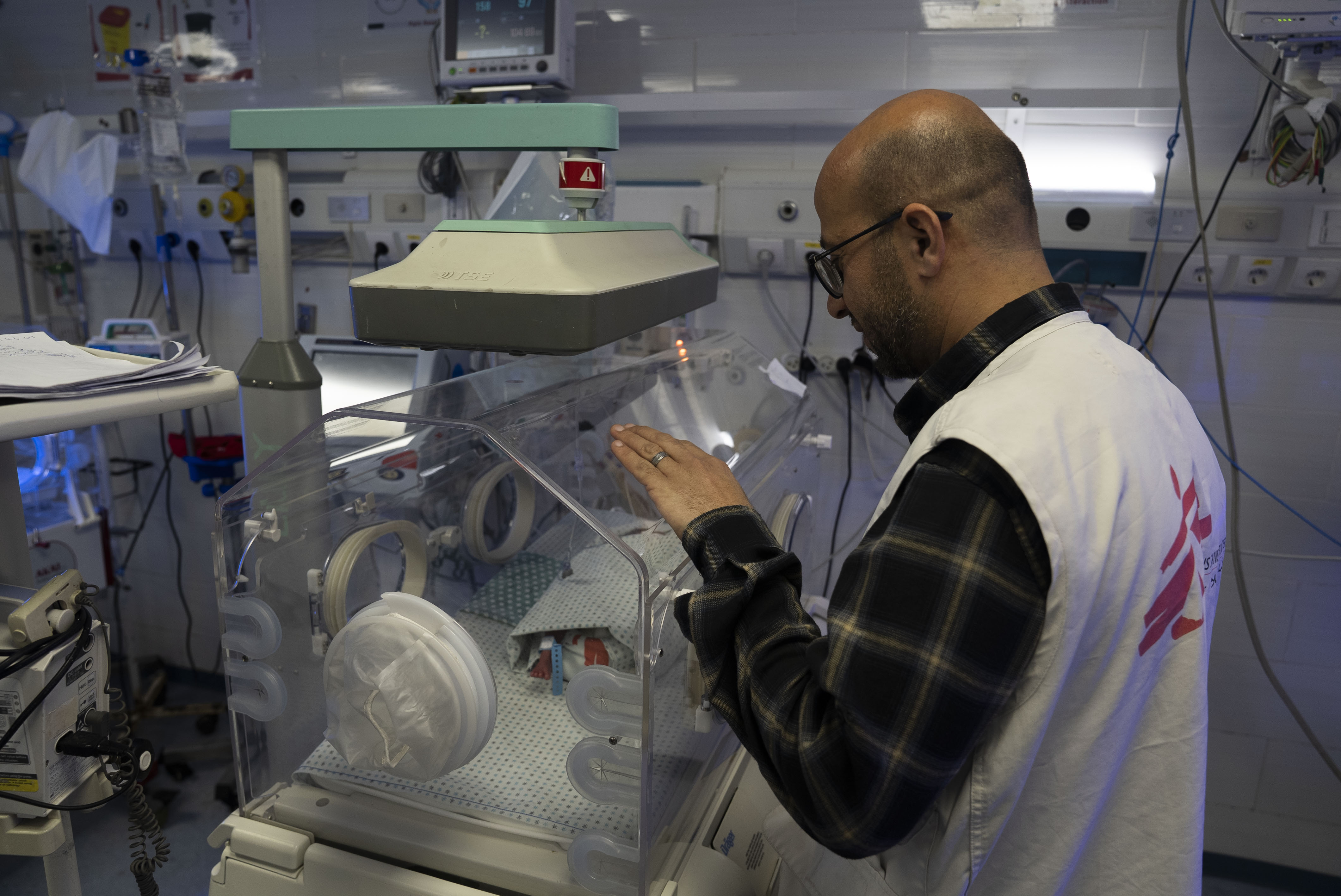 Baby in couveuse met AZG-medewerker die ernaast staat
