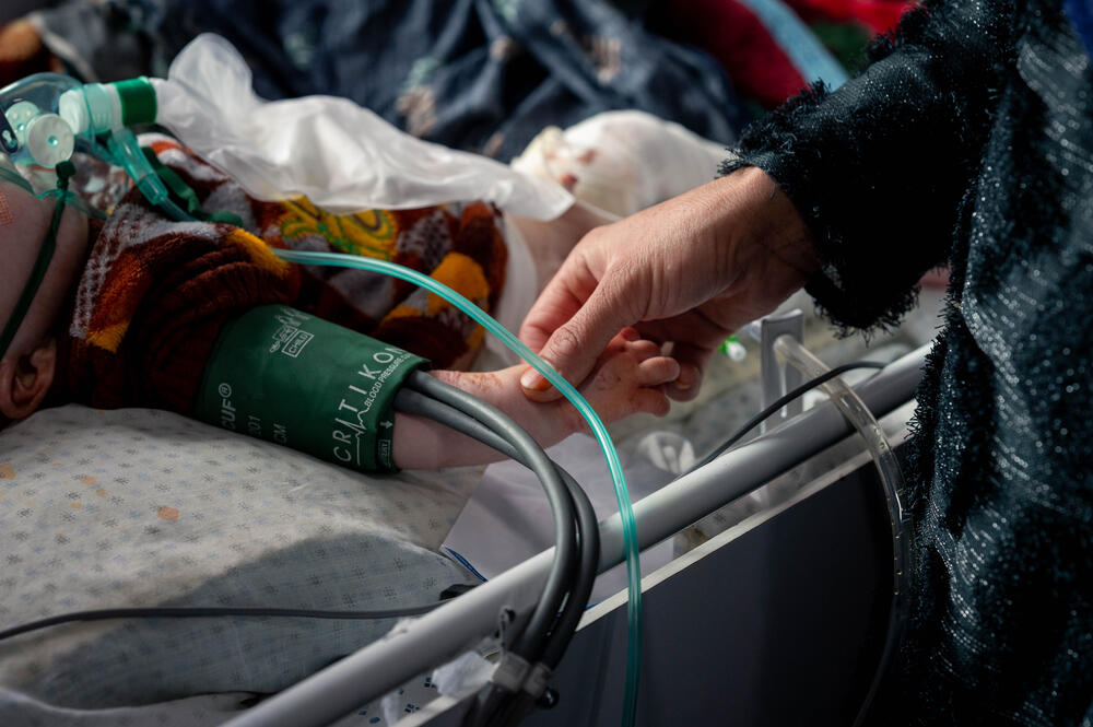 Dans un hôpital de Kaboul, une mère tient la main d'un enfant souffrant de malnutrition, soigné par MSF.