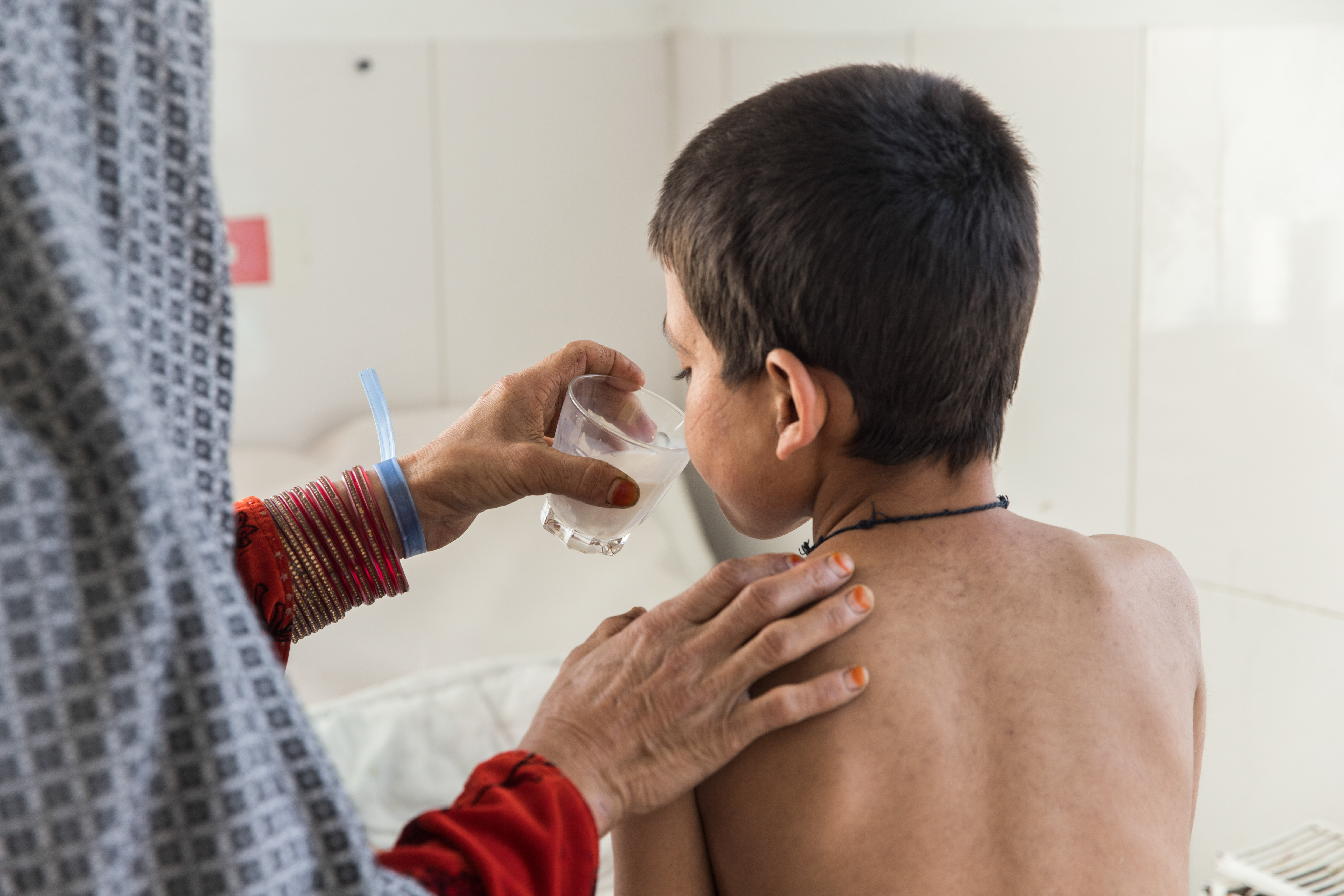 Saed Bibi geeft een glas melk aan haar zoon Saddiqulah, 10 jaar, op de pediatrische afdeling van het door Artsen Zonder Grenzen gesteunde Boost-ziekenhuis in Lashkar Gah, provincie Helmand. Saddiqulah heeft mazelen waardoor hij een longontsteking en ernstige bloedvergiftiging heeft opgelopen. 