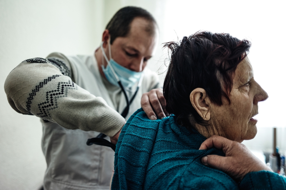 Een dokter van AZG luistert naar het lichaam van een 73-jarige patiënt in Kamenka. © AZG/Misha Friedman