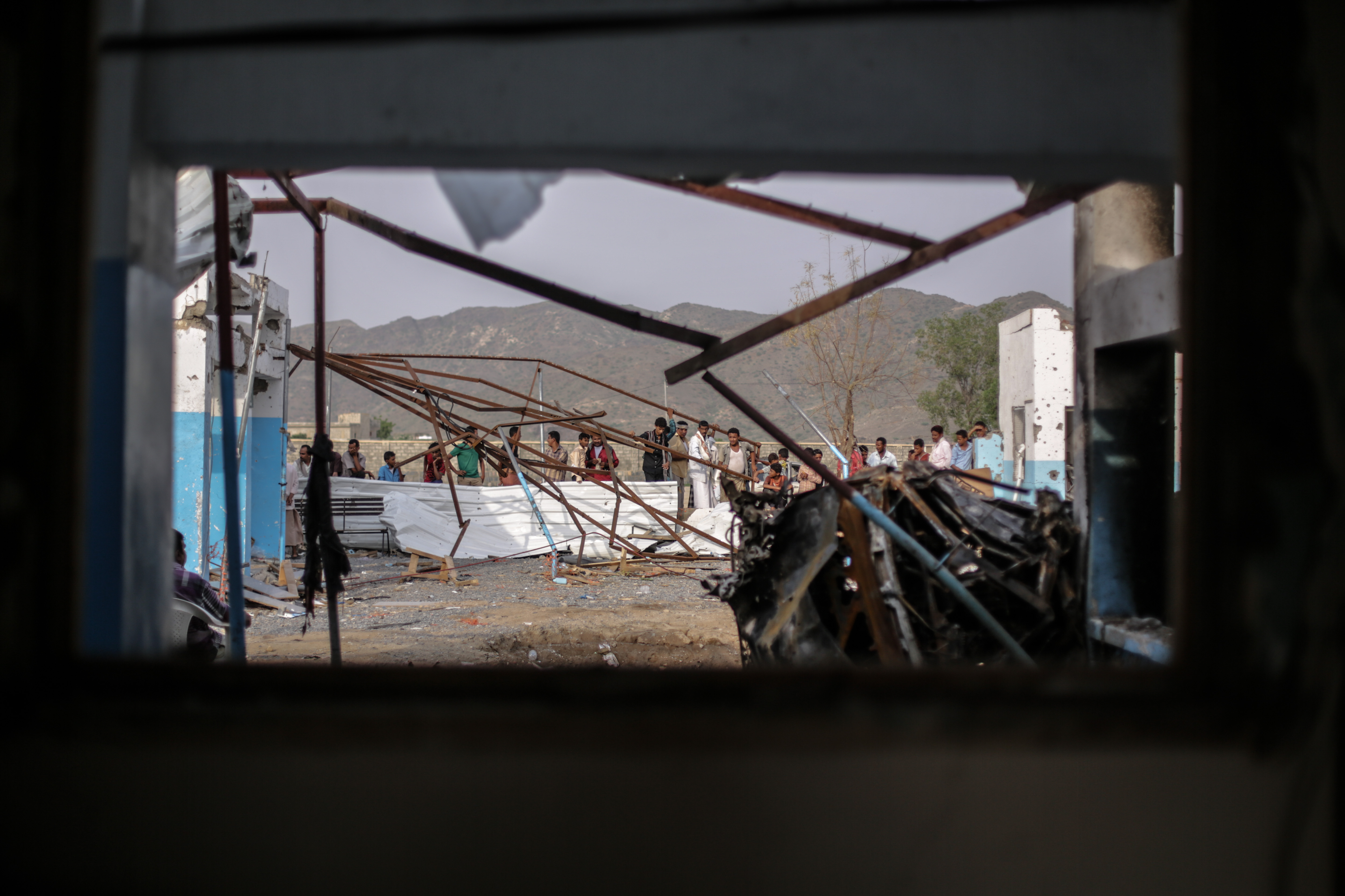 Des hommes et des enfants se rassemblent autour des bâtiments détruits de l'hôpital Abs à Hajjah, au Yémen, pour examiner les dégâts causés par la frappe aérienne de la coalition menée par le gouvernement saoudien le 15 août 2016. Cette attaque a tué 19 personnes et en a blessés des dizaines. © Rawan Shaif