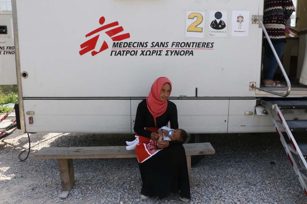 Une femme et son bébé attendent des soins médicaux à la clinique mobile de MSF, en face du camp de réfugiés de Moria.