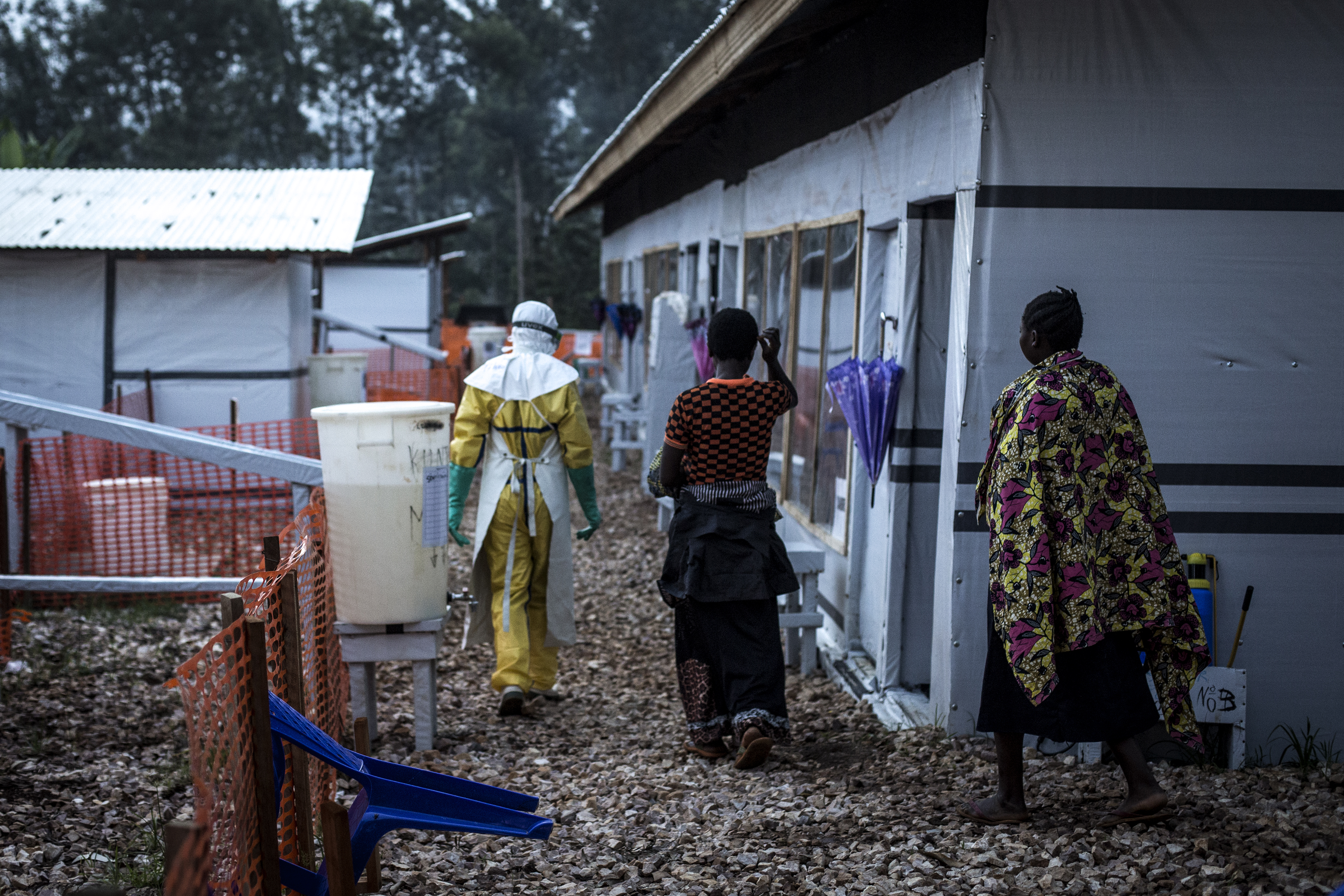 Un travailleur de la santé escorte deux femmes, suspectées d'être atteintes du virus Ebola, dans le centre de traitement Ebola de Butembo. © John Wessels en novembre 2018