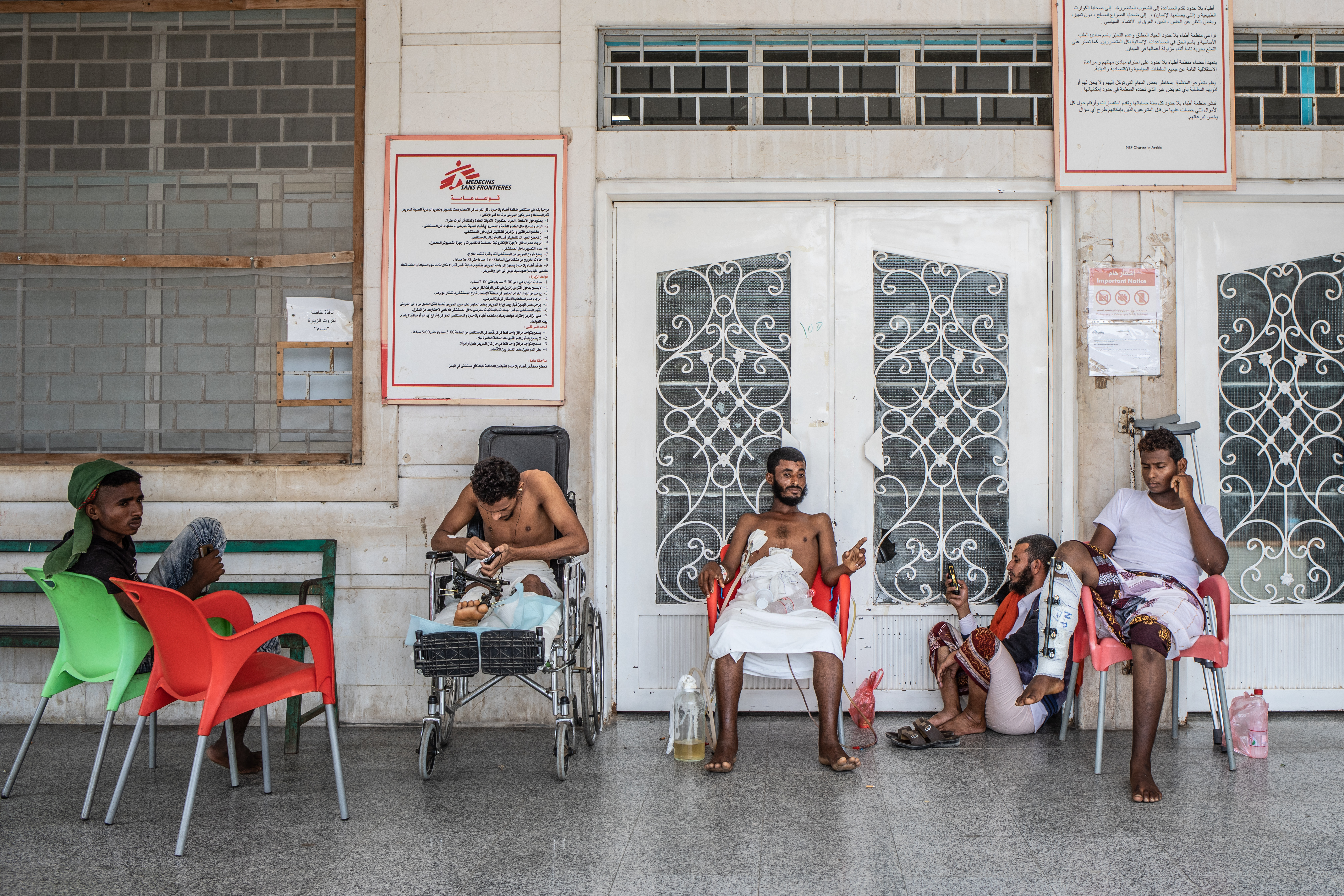 Een aantal patiënten zitten voor de ingang van het chirurgisch ziekenhuis in Aden. Het ziekenhuis behandelt oorlogsslachtoffers sinds 2012. © Agnes Varraine-Leca/AZG, december 2018.