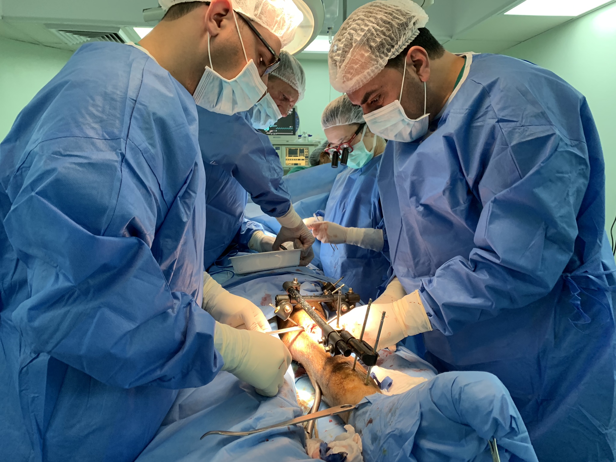 MSF surgeons Hiroko Murakami, Mohammed Obaid and Henri Vandenboer work with MSF nurse Mohamed Alramlawi to carry out a bone graft on Yousri*, a patient from Gaza shot by the Israeli army during protests in July 2018. Al-Awda Hospital