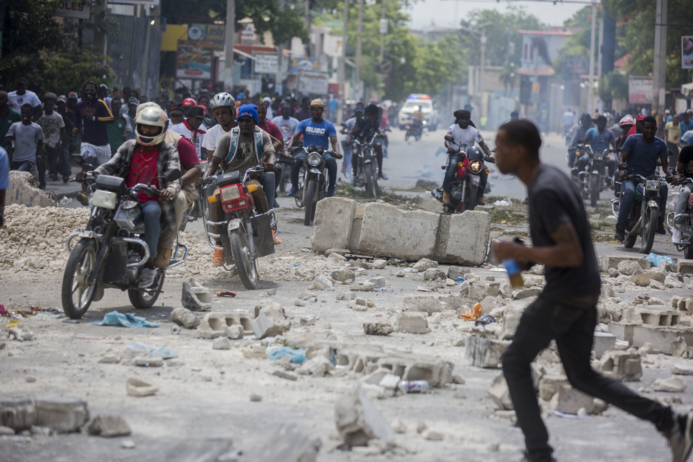 Wegversperringen bemoeilijken het verkeer. Hier wordt een straat gebarricadeerd tijdens gewelddadige protesten Port-au-Prince 