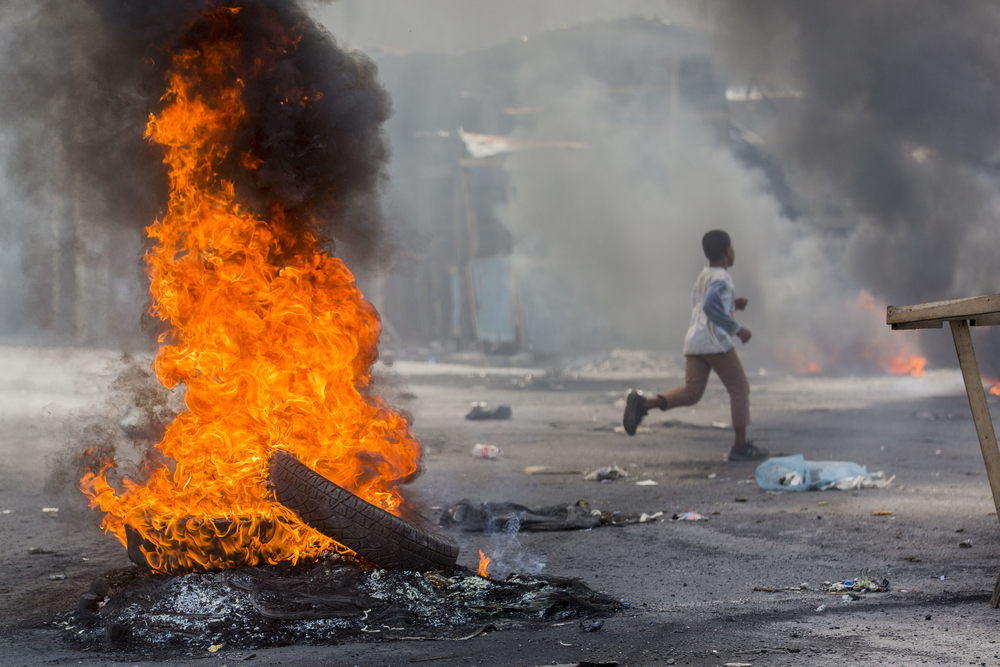 Un garçon court dans une rue bloquée par des pneus en feu lors d'une manifestation à Port-au-Prince le 13 juin 2019 © Jeanty Junio Augustin 