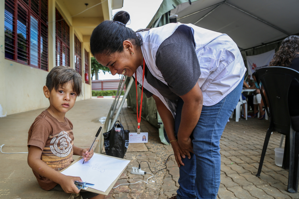 MSF health promoter Tonanzin Urrieta talkes with a Venezuelan child in a therapeutic workshop. In Jardim Floresta shelter, the MSF mental health team promotes specific activities for children, from age 3 to 6 years old. They talk about topics such as protection against abuse and situations of violence. They also address self-esteem issues, because some of the children are being bullied or have gone through this situation before.