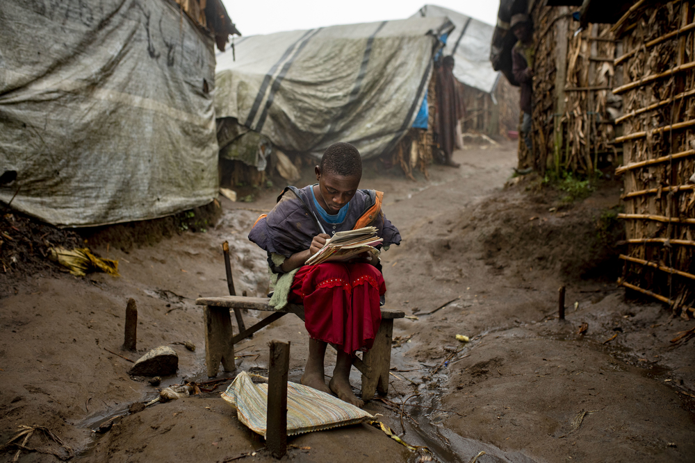 Une fille de 12 ans profite des dernières lueurs du jour pour faire ses devoirs devant sa « maison » dans le camp de déplacés de Katale.