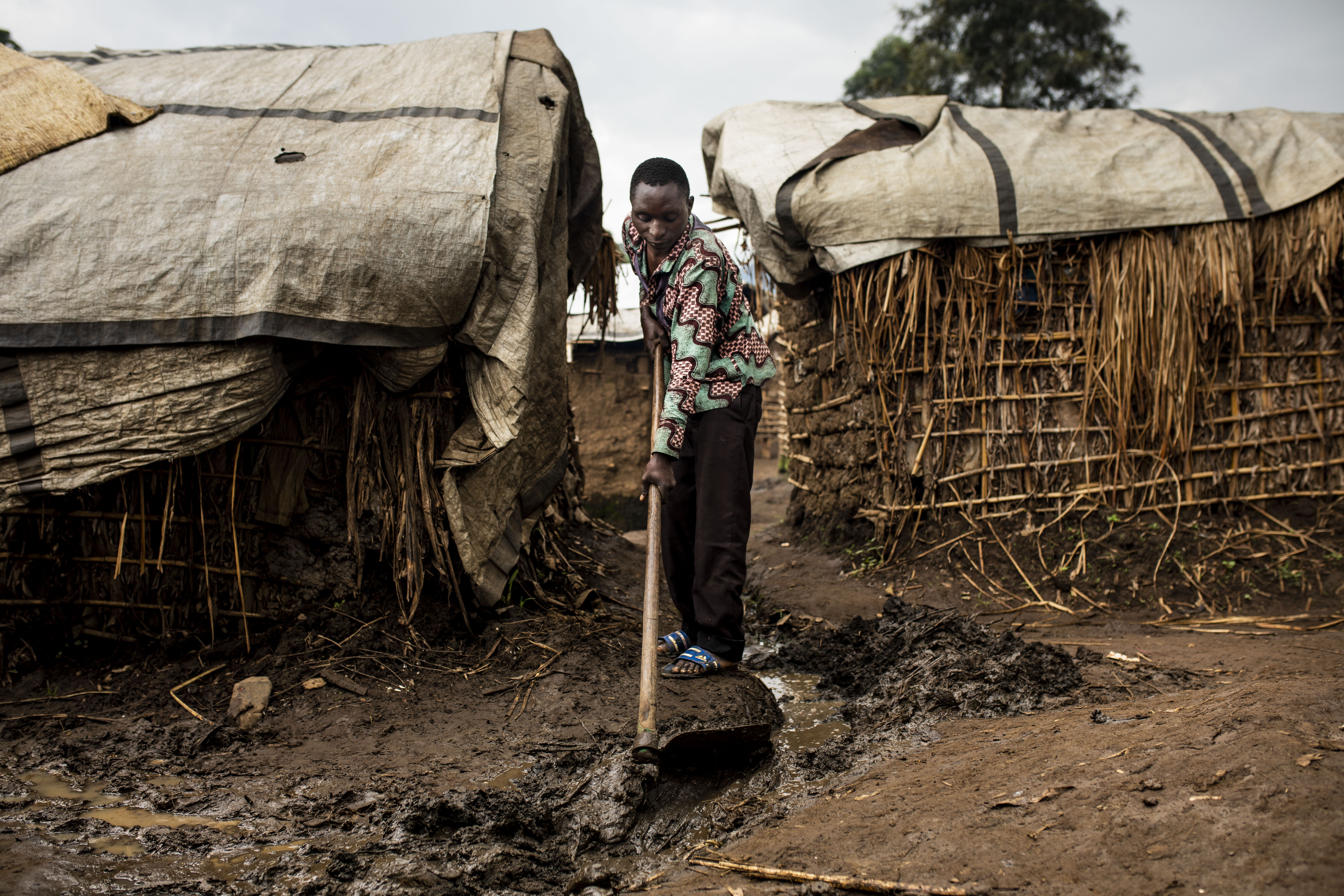 Aan het begin van het regenseizoen probeert deze man de afvoer rond zijn huis in het kamp van Bukombo uit te graven. In het kamp zijn niet genoeg toiletten en afvalwater stroomt vrij doorheen het kamp.