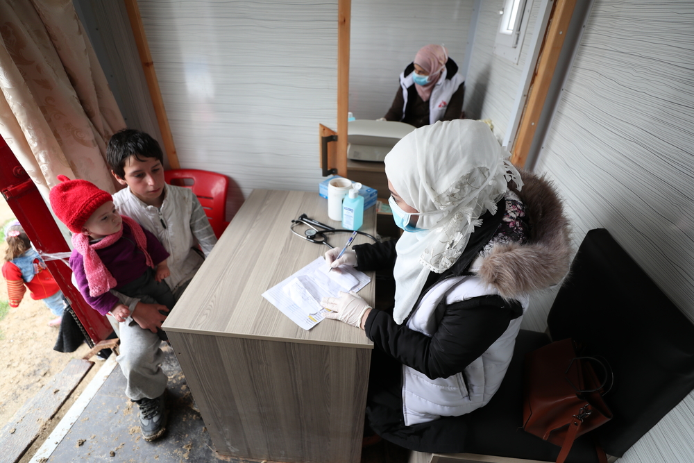 Onze verpleegkundige praat met twee kinderen tijdens een consultatie in onze mobiele kliniek. © Omar Haj Kadour. 31 maart 2020.