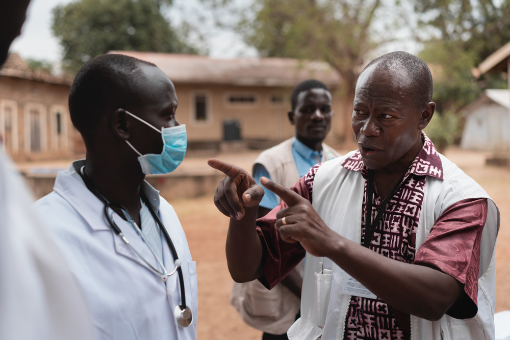 Water- en sanitatiespecialist Adrien Mahama toont een correct gebruik van een mondmasker aan het personeel van het Al Sabah-ziekenhuis in Juba, Zuid-Soedan. 
