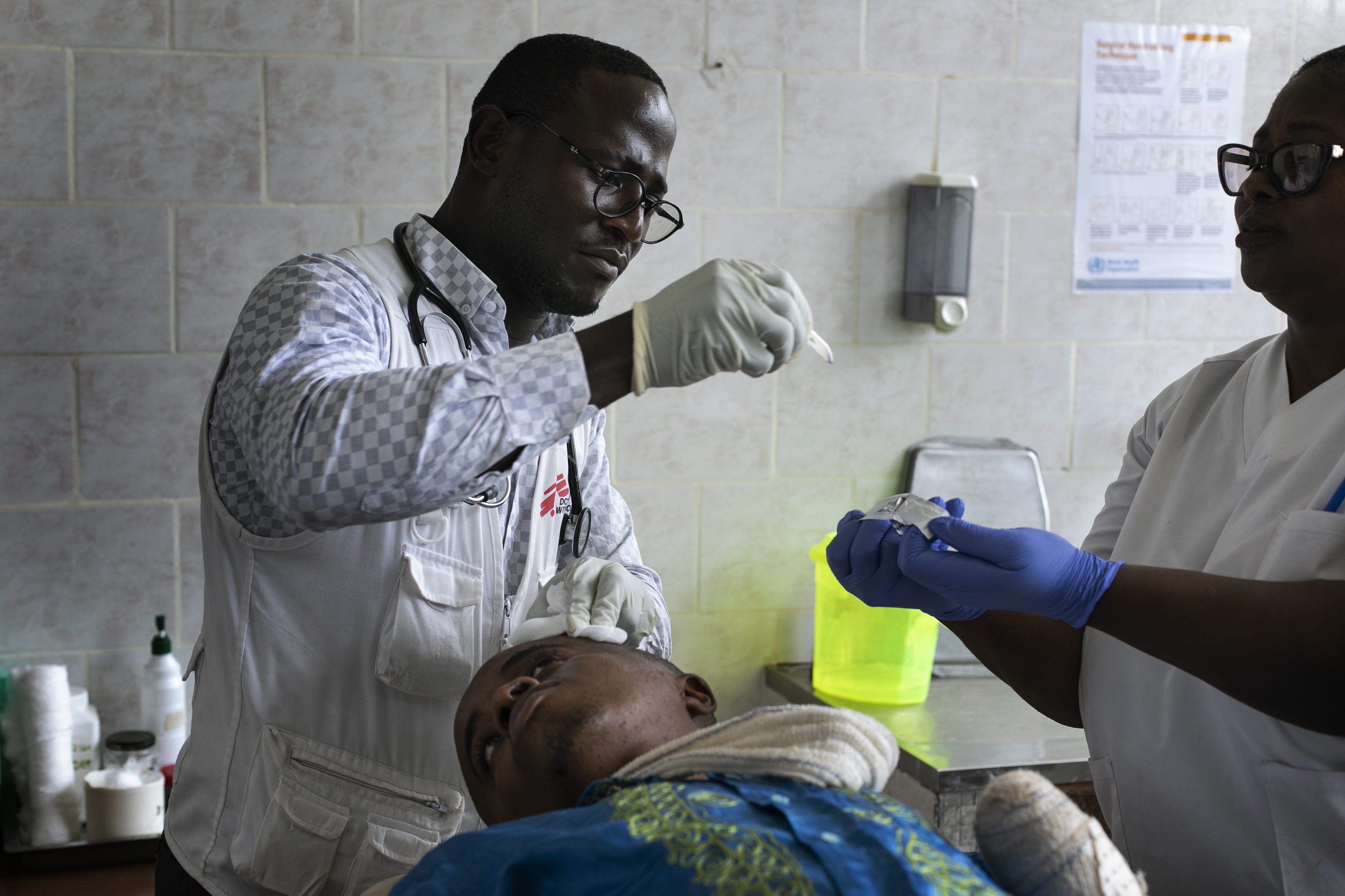 Dokter Jifon verzorgt de wonde van Felix tijdens een follow-up. Felix herstelt wonderwel. De infectie aan zijn linkerarm is volledig genezen. © Albert Masias, maart 2020.