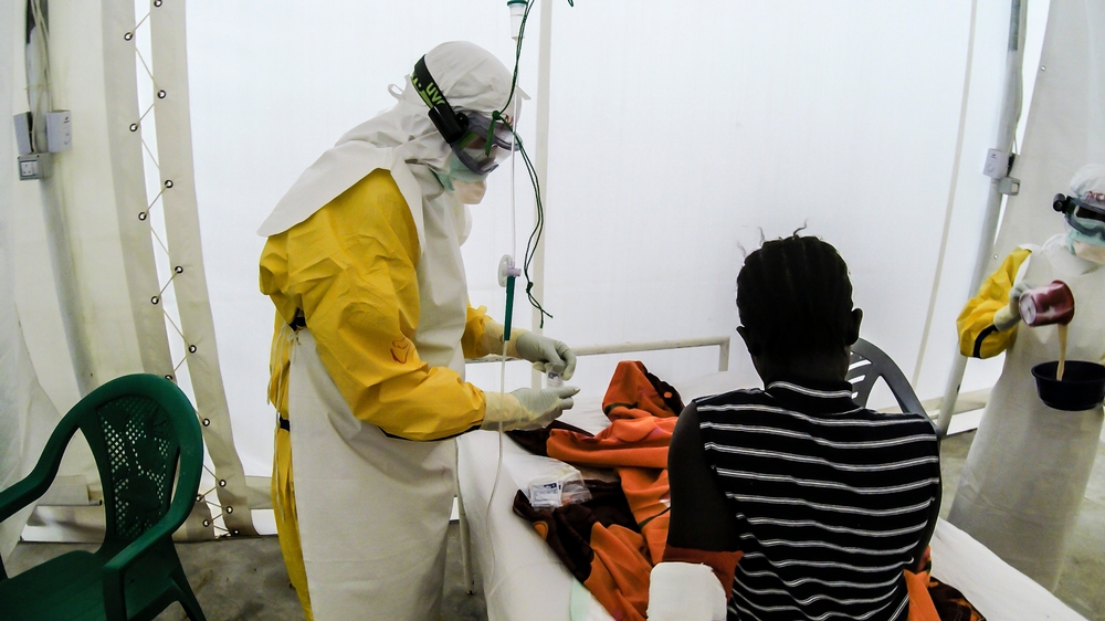 Medisch personeel van Artsen Zonder Grenzen, in de typische beschermende pakken, verzorgt een meisje van zestien in een ebolakliniek tijdens de gigantische ebola-uitbraak van 2014-2015. Fabio Basone/MSF. Sierra Leone, 2015.