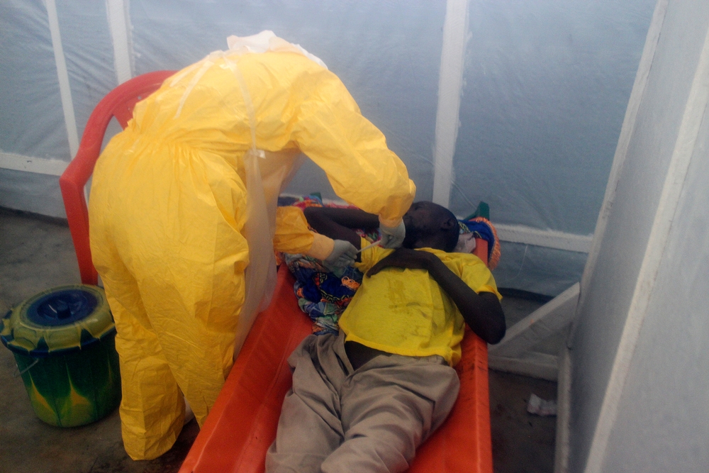 Een medewerker van Artsen Zonder Grenzen neemt de temperatuur van een ebolapatiënt in Conakry. © Amandine Colin, 2014.