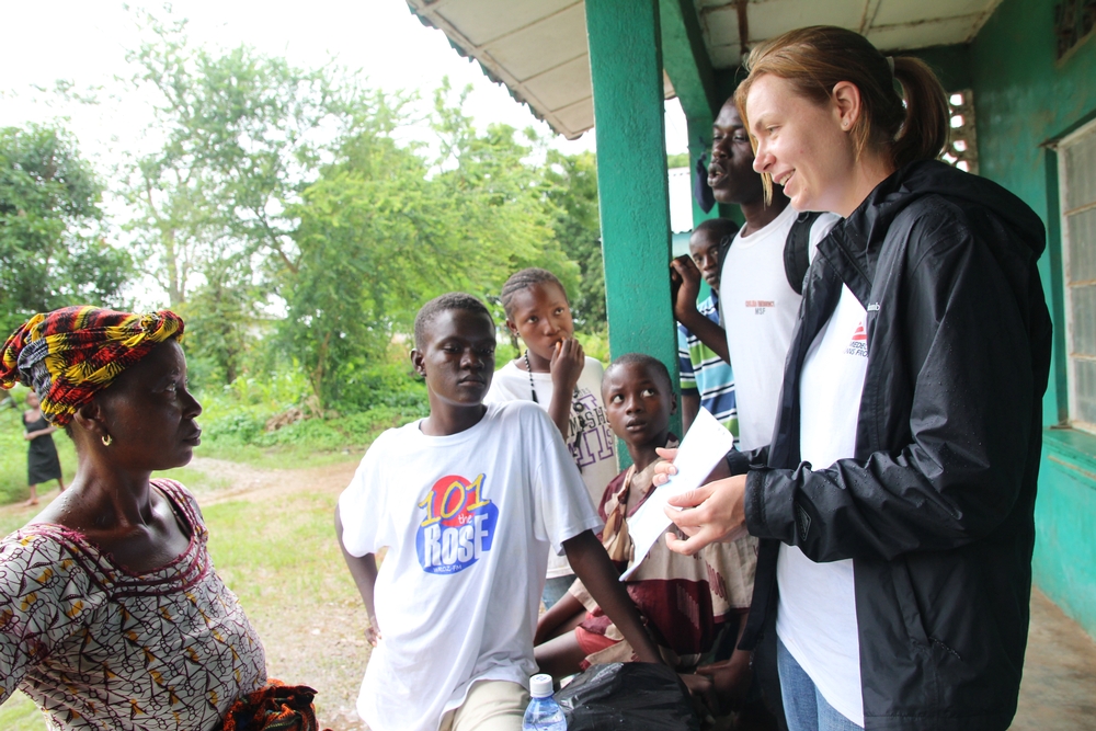 Ella toont aan de moeder van een ebola-patiënt het bewijs waarop staat dat haar zoon volledig is genezen.