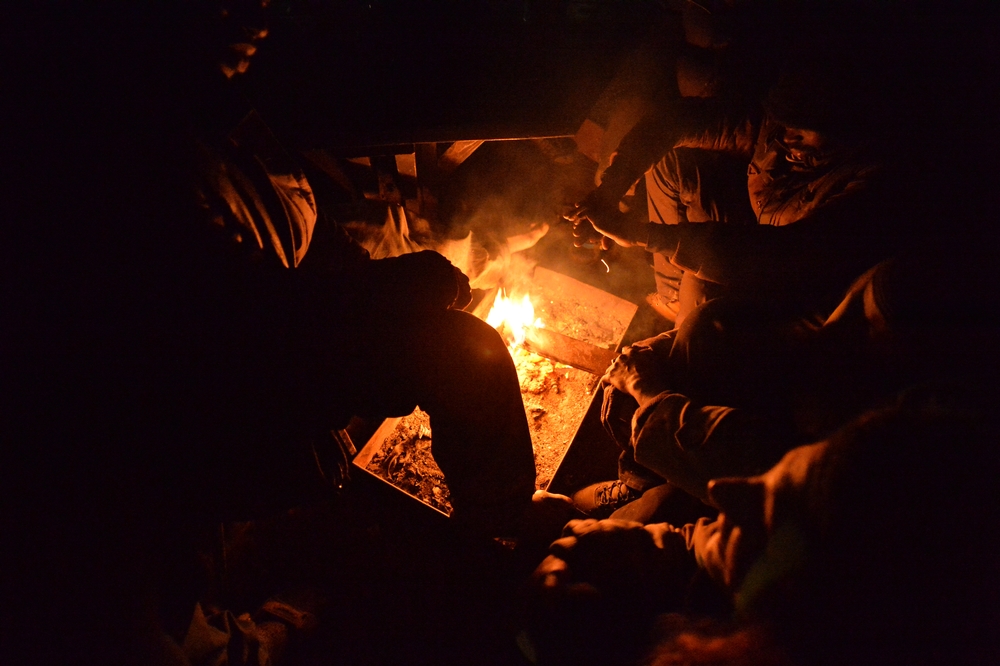Un groupe d’hommes de Côte d’Ivoire, de Gambie, du Mali et du Togo se tiennent chaud près d’un feu de camp à proximité du centre d’asile de Bogovadja. Au total, ils disposent de 2 sacs de couchage pour 10 personnes. 