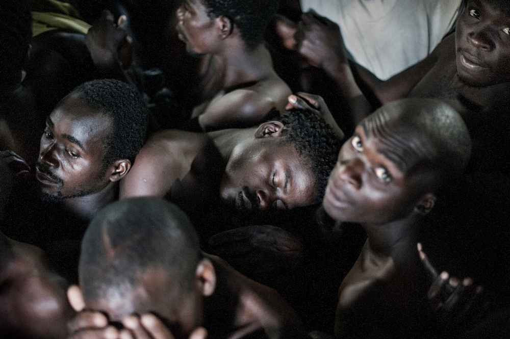 Les détenus sont assis la nuit dans une cellule surpeuplée et tentent de dormir © Luca Sola