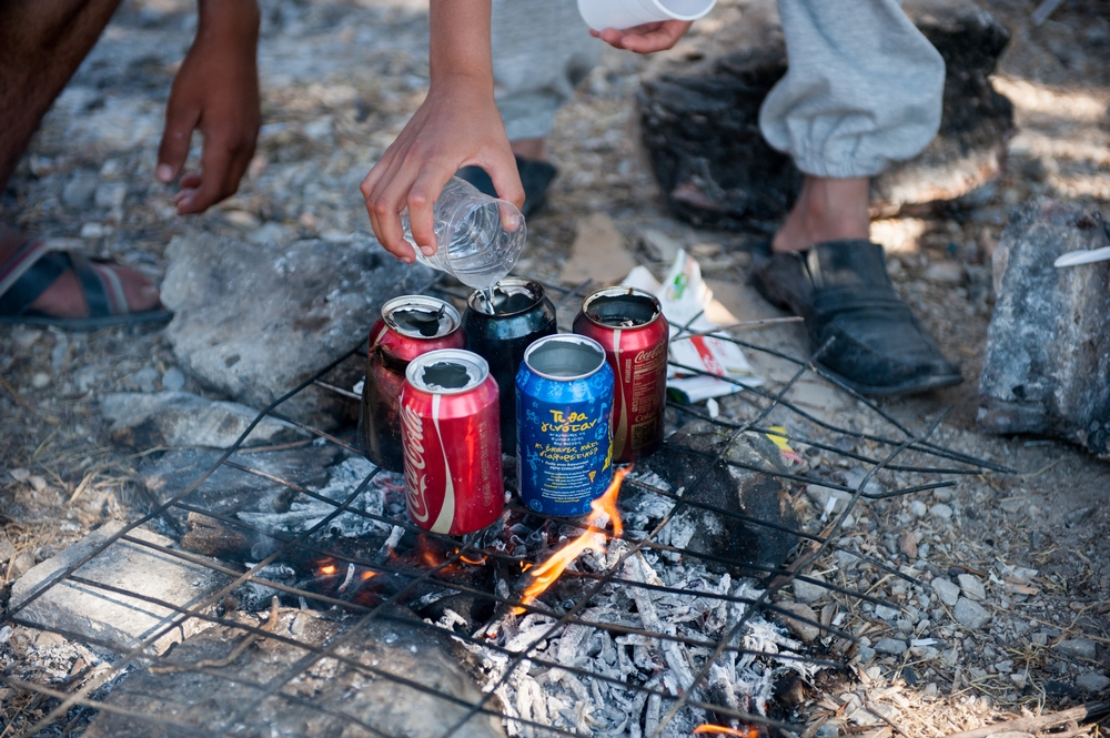 Mensen gebruiken lege colablikjes om water te koken voor hun thee in het Kara Tep-kamp,  © Georgios Makkas/AZG 
