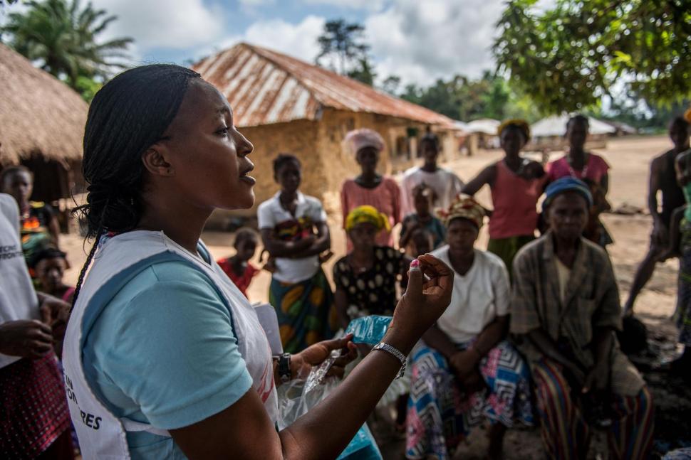 Voorlichter Emma Kamara spreekt met mensen in een dorp in Sierra Leone over de hulp die Artsen zonder Grenzen biedt aan mensen die ebola overleefd hebben. Vele overlevers kampen met fysieke en mentale problemen. © Tommy Trenchard