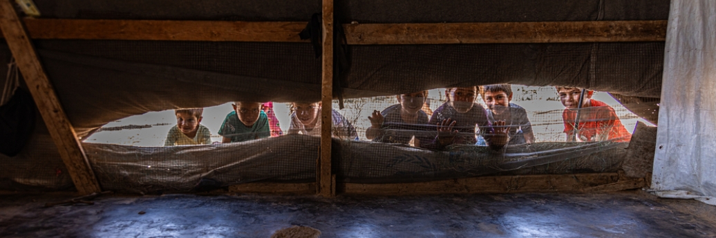Des enfants syriens regardent à travers la fente d'une tente
