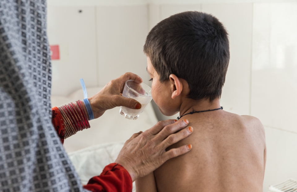 Saed Bibi geeft een glas melk aan haar zoon Saddiqulah, 10 jaar, op de pediatrische afdeling van het door Artsen Zonder Grenzen gesteunde Boost-ziekenhuis in Lashkar Gah, provincie Helmand. Saddiqulah heeft mazelen waardoor hij een longontsteking en ernstige bloedvergiftiging heeft opgelopen. 