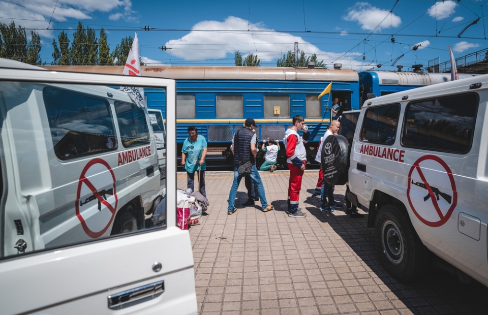 Une ambulance MSF, des membres de notre équipe et un train médicalisé en fond