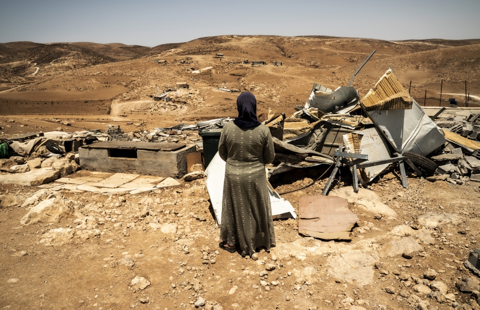 Une femme se tient devant les maisons détruites