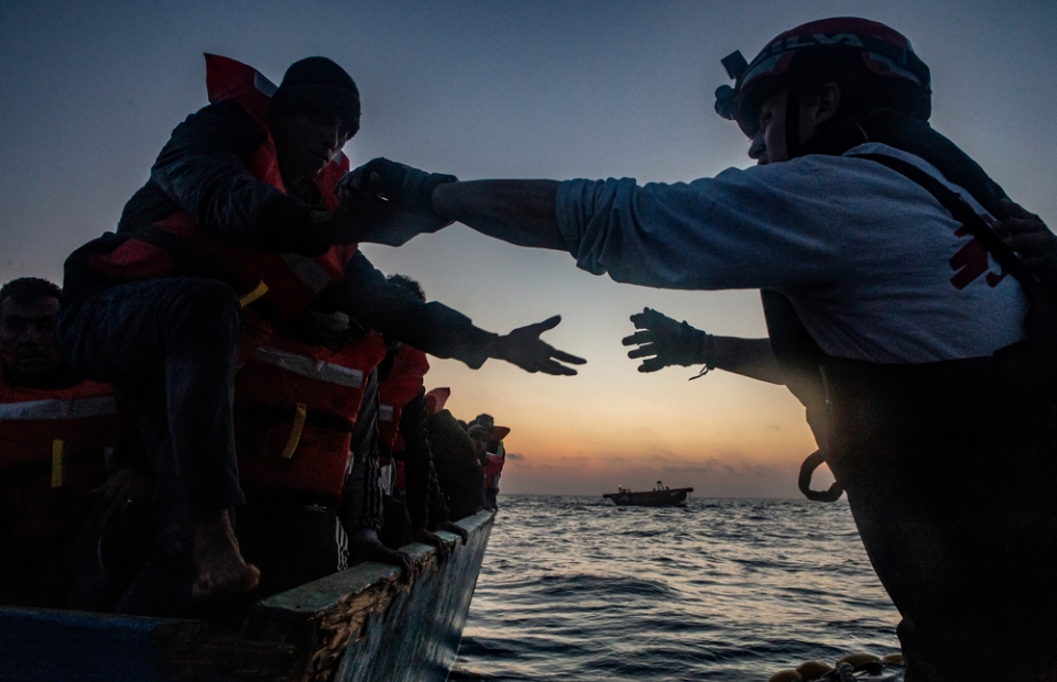 L'équipe de MSF tend la main à une personne pour la sortir d'un petit bateau