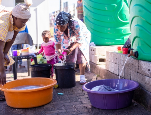 vrouwen in Zuid-Afrika nemen water uit een ton