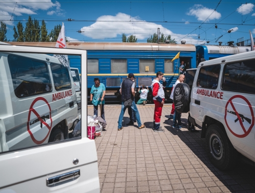 Une ambulance MSF, des membres de notre équipe et un train médicalisé en fond