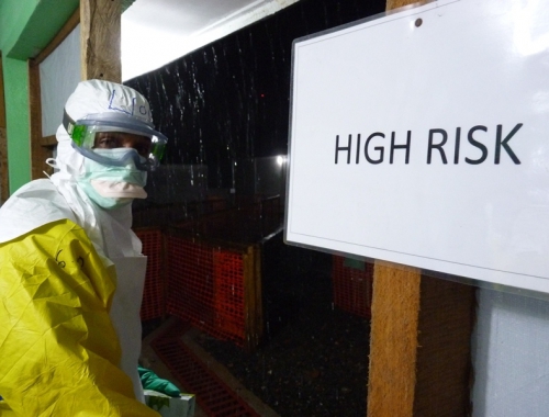 Un collaborateur en combinaison Ebola devant un centre de traitement
