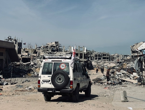 An MSF vehicle passes in front of ruined buildings in Jabalia.