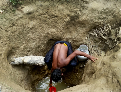 Een man haalt water uit een met de hand gegraven waterput in het kamp Unchiparang. Maar ook op drie meter diepte is water niet noodzakelijk drinkbaar. © Paul Andrew Jabor/AZG