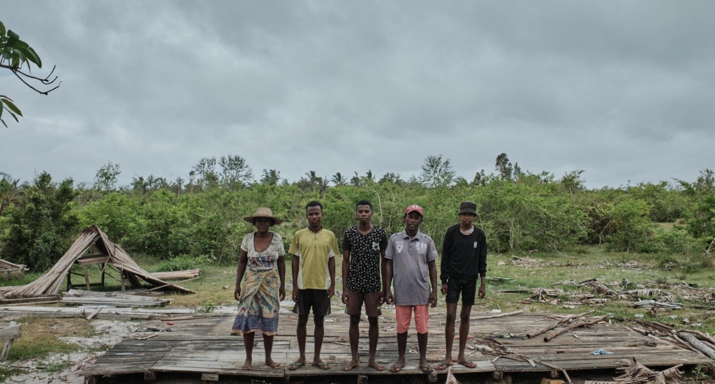 Portret van Aurelien Andriamanantena Tsiva met zijn gezin voor hun huis in Nosy Varika, verwoest door de cycloon Batsirai