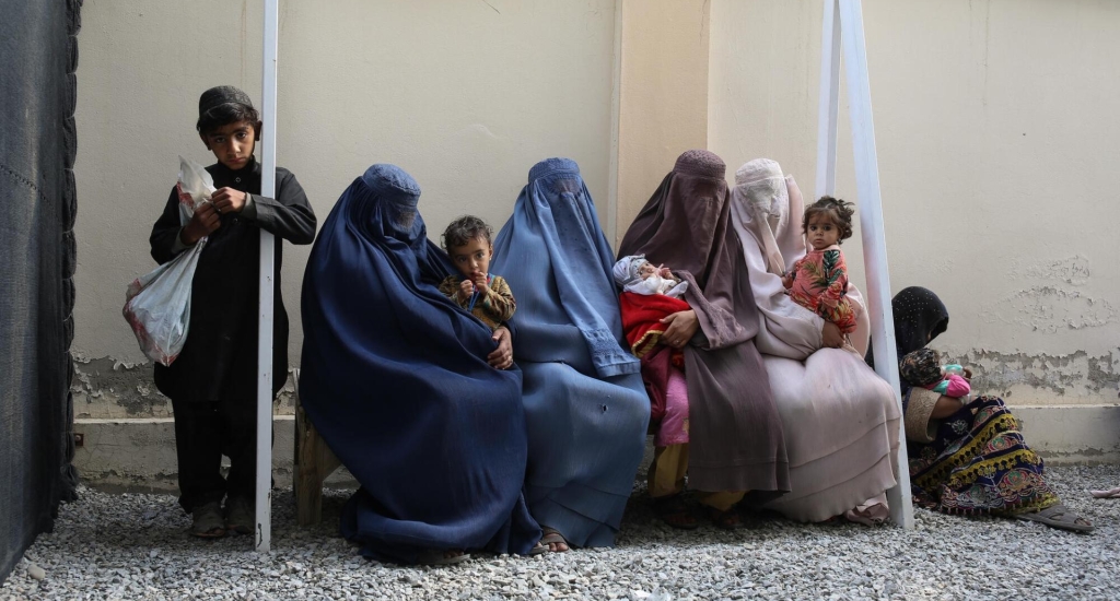 Un groupe de femmes et d’enfants attendent sur un banc dans le centre nutritionnel thérapeutique de MSF 