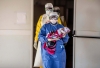 Een medewerker staat voor een behandelingscentrum van AZG en draagt een kindje naar binnen. ©Tommy Trenchard/AZG 